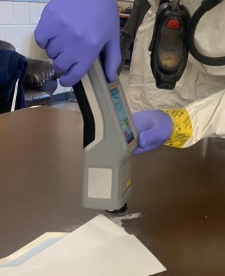 Handheld ResQ in use on table with envelope and white powder.